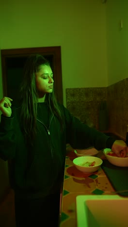 young woman preparing food in a kitchen with colorful lighting