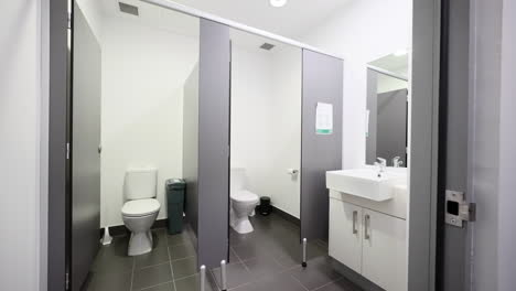 female public toilet restroom clean grey interior with private stalls and sanitary waste box