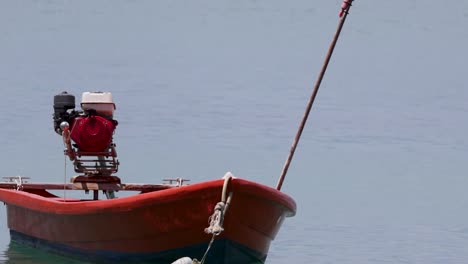 a red boat with an engine is moored on calm waters, showcasing a peaceful maritime scene.