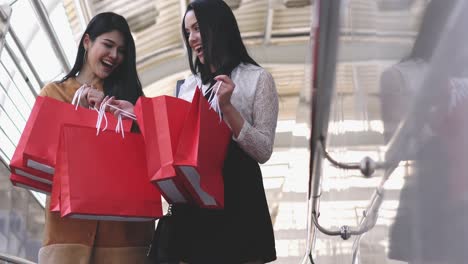 beautiful young woman shopping together in city. lady holding red shopping bag on hands.