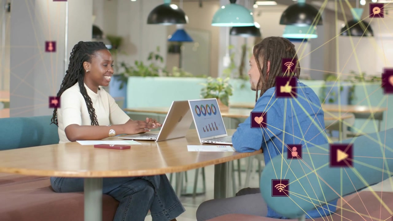 Marketers at table, right leaning and gesturing, sparking social icons while left analyzing metrics