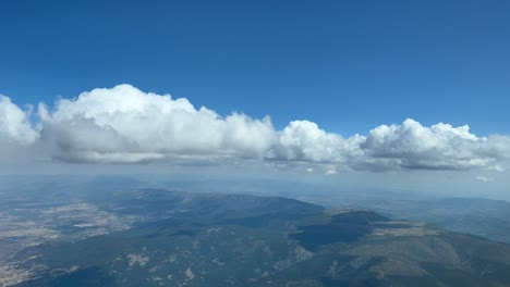 punto de vista piloto único durante el descenso para la aproximación al aeropuerto de madrid, con algunos cúmulos diminutos y un cielo azul profundo