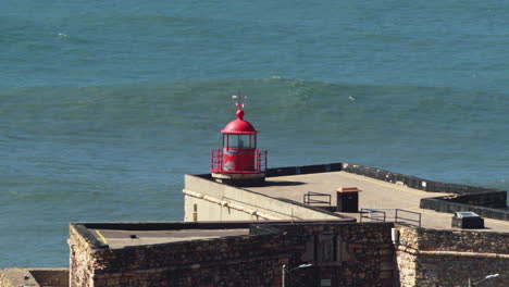 faro de nazaré con grandes olas en el fondo