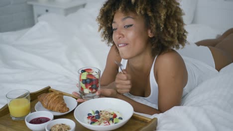 Dreaming-woman-having-sweet-meal-in-bed