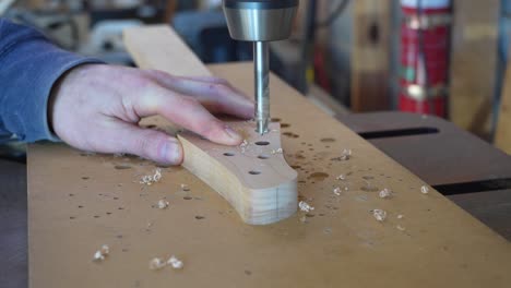 luthier perforando agujeros en el clavijero para un nuevo proyecto para insertar afinadores