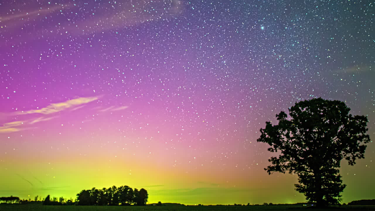 Vibrant Starry Night Sky with Aurora-like Colors and Solitary Tree