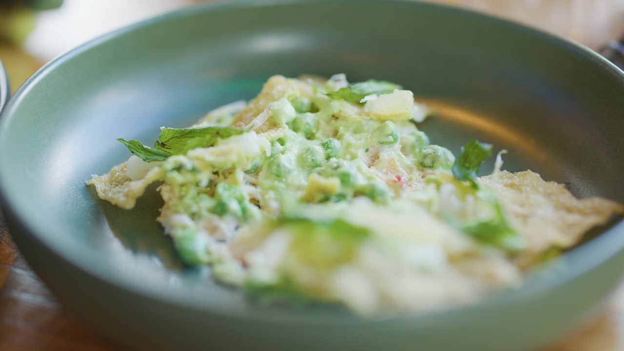 Fork lifts gourmet crab cake with fresh greens in natural light, showcasing fine dining detail