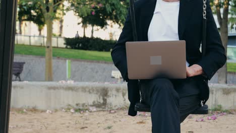 man working on laptop while sitting on a swing in a park