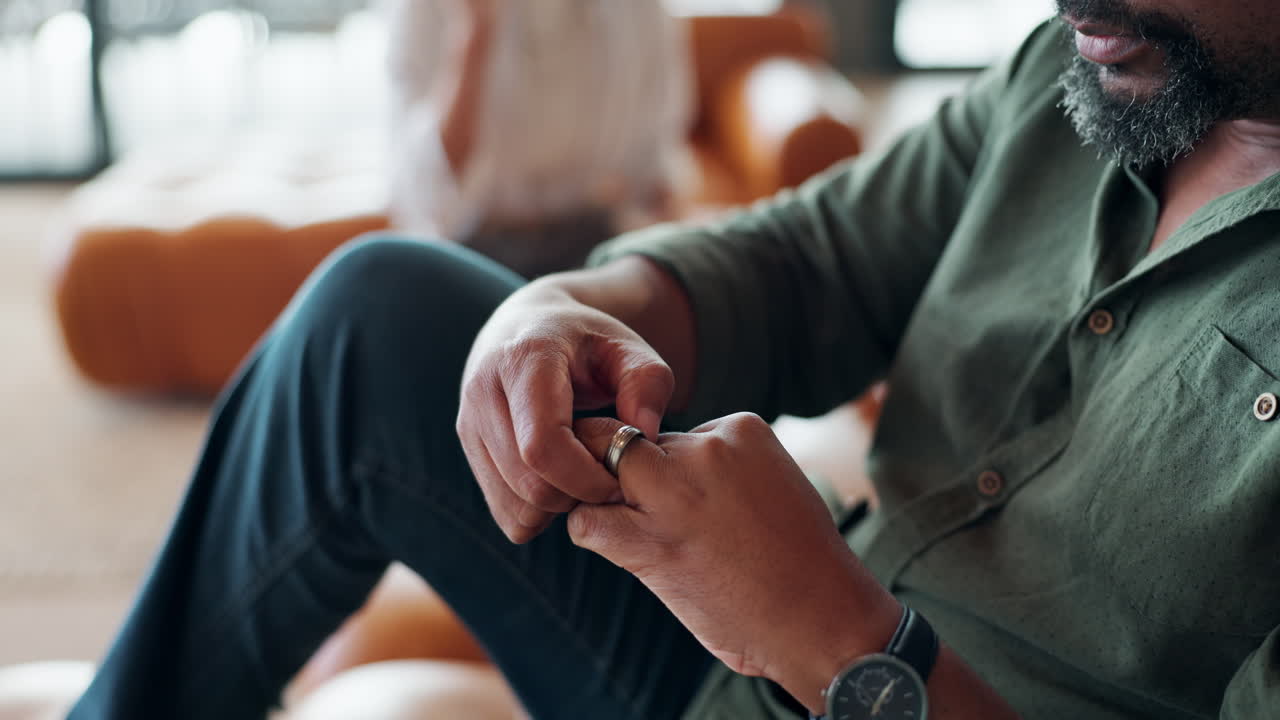 A man wearing a wedding ring sitting indoors