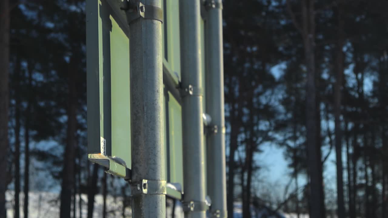 Traffic sign that has melting snow water dripping on it from above and water is splashing around during impact in slow motion. Winter sunny day with traffic sign in focus and background trees blurred.