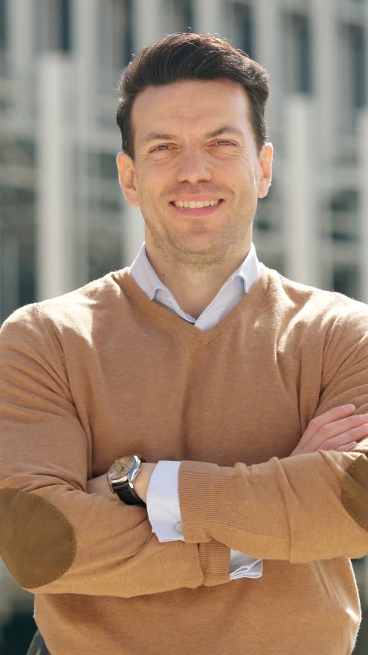 Portrait of a smiling man with crossed arms in a brown sweater