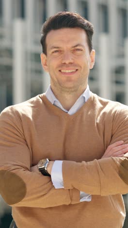 portrait of a smiling man with crossed arms in a brown sweater