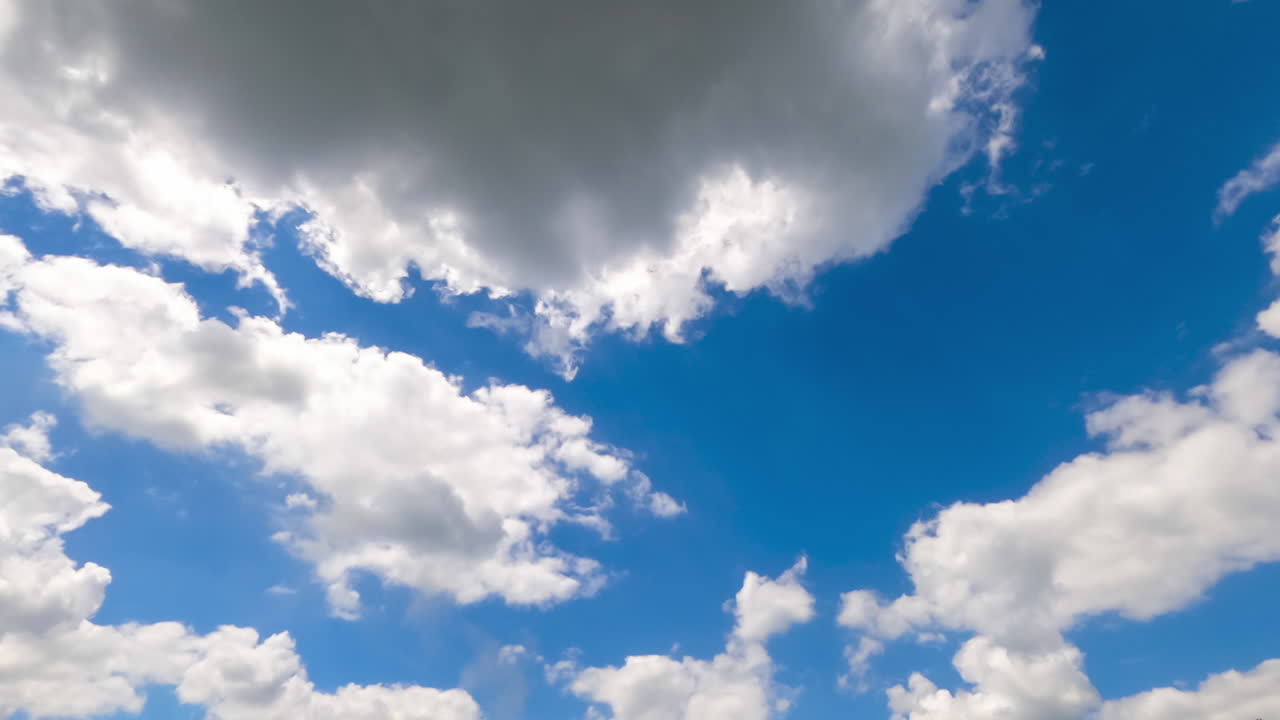 Soft puffy clouds quickly changing shape. Sun rays passing through the cloudscape. Timelapse.