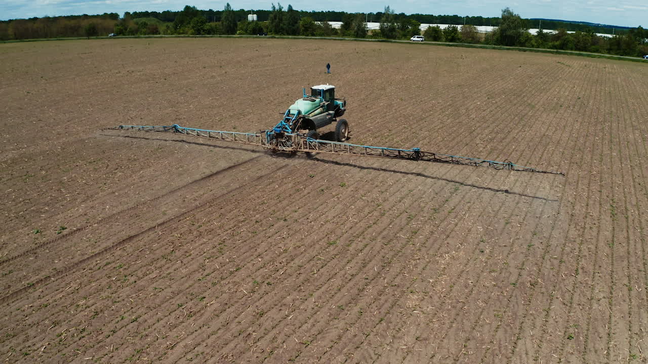 Treatment of fields with pestecides. Aerial view of tractor spraying pesticides on field