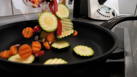 primer plano de una mujer poniendo varias verduras sabrosas en la sartén caliente para freír una receta vegetariana o vegana en la cocina