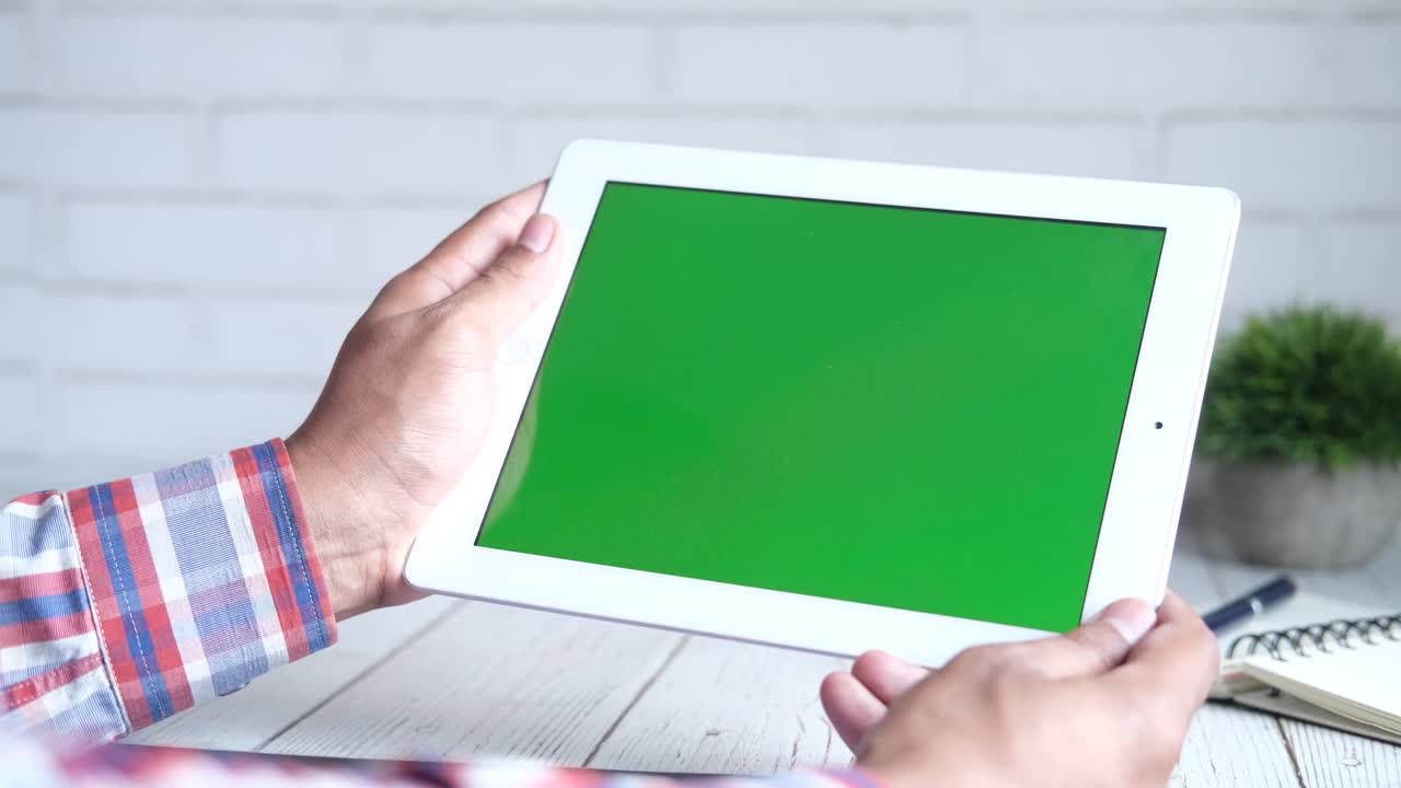 persona que sostiene una tableta con una pantalla verde