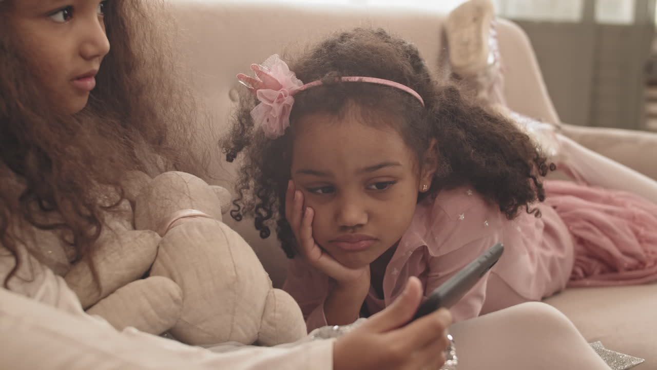 Little Sisters Using Smartphone on Couch