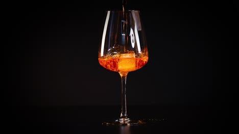 pouring aperol spritz into a wine glass