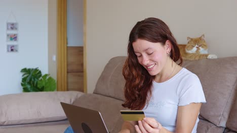woman shopping online with laptop and credit card with her cat nearby