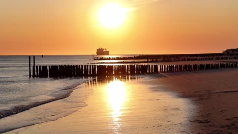 Beautiful sunrise scenery, old wooden pier and backdrop of distant ship