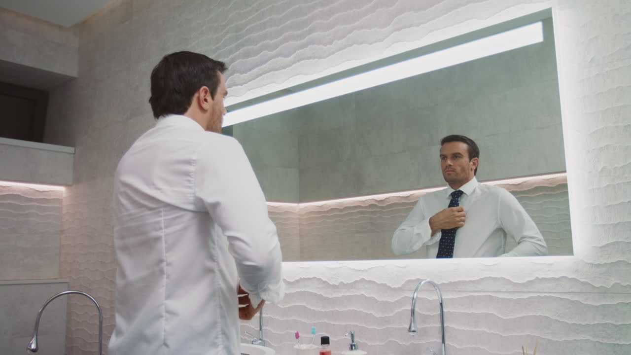 Uomo d'affari che indossa la cravatta in un bagno di lusso. Uomo felice che si veste in casa