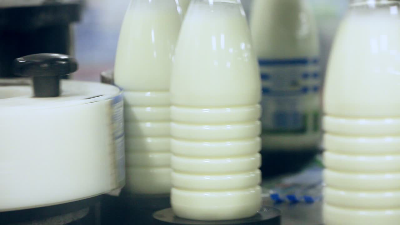 máquina de etiquetado en la línea de producción de leche. etiquetado de botellas de leche. etiquetado de productos