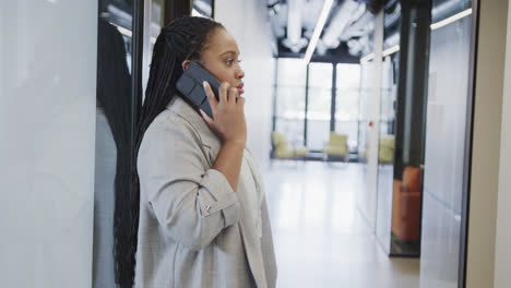 Worried-african-american-casual-businesswoman-talking-on-smartphone-in-office-corridor,-slow-motion