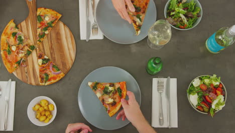 overhead view of friends eating pizza in restaurant together