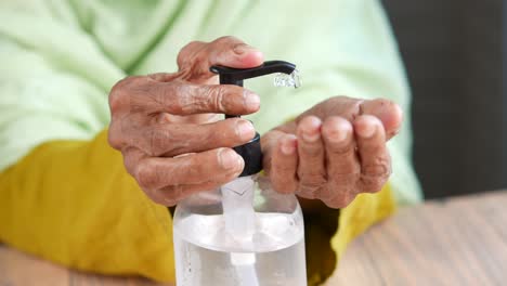 persona de edad avanzada que utiliza desinfectante para las manos
