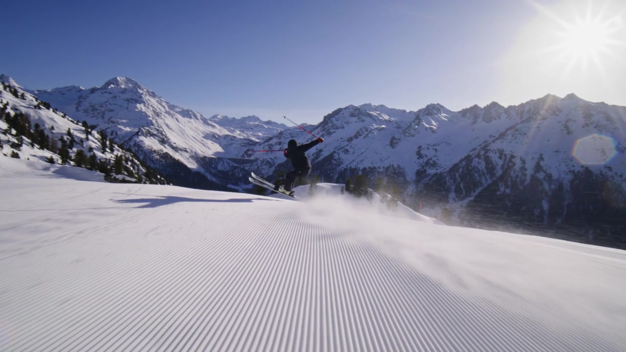 Skier carving groomed pistes at high speed in Nendaz, part of the 4 Vallées ski area in the Swiss Alps. Elite alpine skiing with powerful snow spray and precision technique.