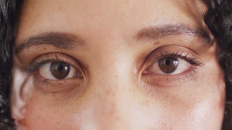 close up portrait of the opening eyes of biracial woman looking to camera, smiling in slow motion