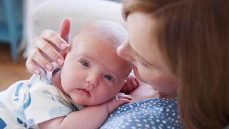 Slow-Motion-Shot-Of-Mother-Sitting-On-Sofa-At-Home-Cuddling-And-Kissing-Baby-Son