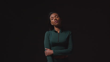 retrato de una atleta femenina decidida que lleva un traje de entrenamiento y se prepara psicológicamente para un evento deportivo contra un fondo de estudio negro 1