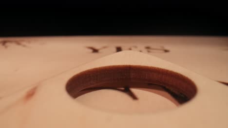 macro shot of a planchette moving across ouija board spelling out words and numbers in bright - macro shot of a planchette moving across ouija board spelling out words and numbers in blue and red flashing lights. ouija boeard session talking to the otherwordly entity. creative mystical content