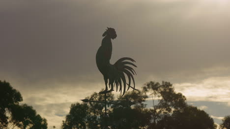 rooster shaped wind vane at dusk-dawn, low angle