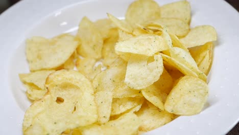 hand reaching for crispy potato chips on a plate