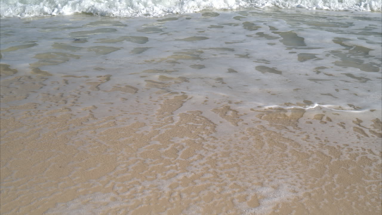 따뜻하고 화창한 날 멕시코 칸쿤의 해변에서 작은 파도를 만드는 물의 느린 동작