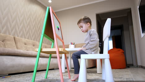young child painting at home easel. a child engages in creative painting at home, using an easel in a cozy living room with soft furnishings