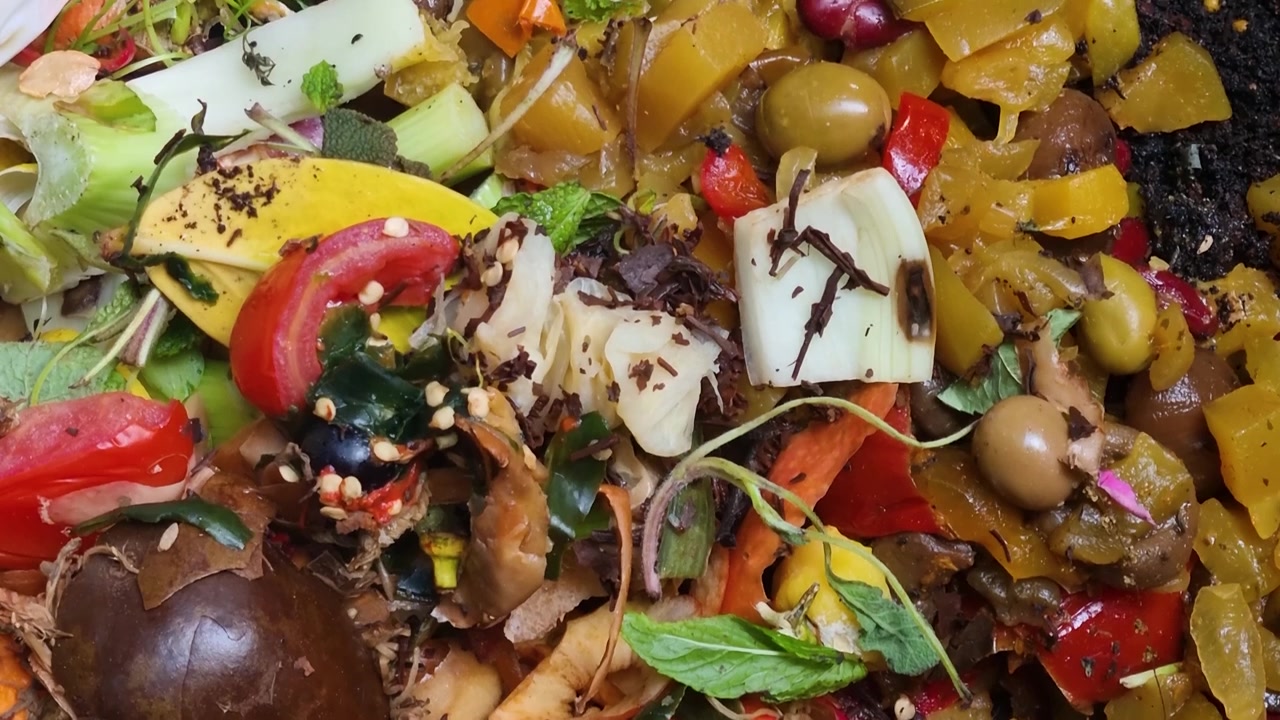 Scatto dettagliato di scarti di cucina organici e rifiuti da giardino all'interno di una compostiera, che mostra il riciclo alimentare ecologico, la biodegradazione e la produzione sostenibile di compost per un terreno più sano