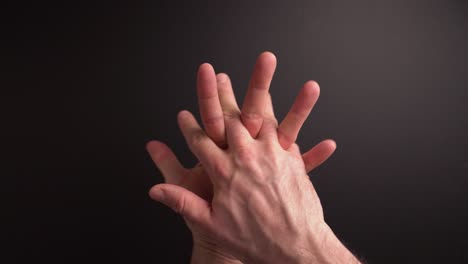a young guy is sanitising his hands with alcohol sanitiser against the virus covid -19. dark background