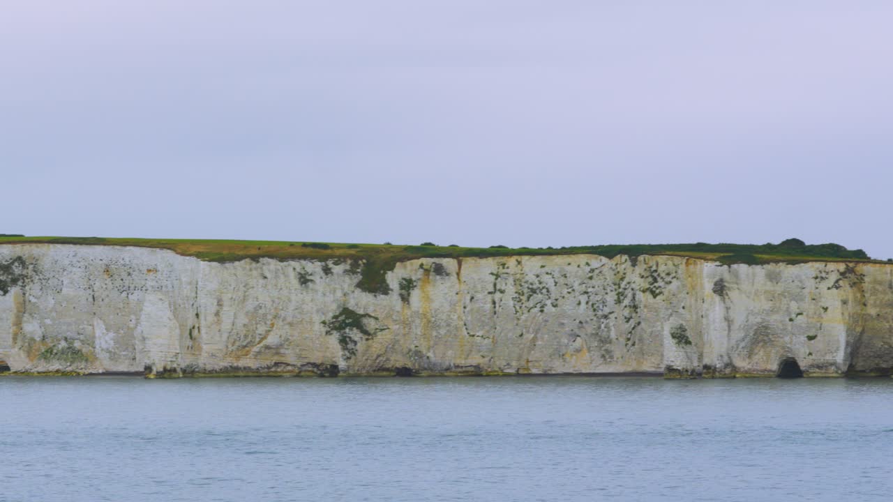 панорамный вид вдоль английского побережья белых меловых скал с полями и спокойным морем в облачный день недалеко от поула, великобритания