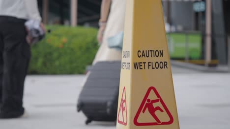 yellow caution wet floor sign in a public area with people passing by