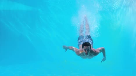 Hombre-En-Forma-Nadando-Bajo-El-Agua-En-La-Piscina