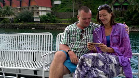 hombre y mujer escuchando música sentados en un banco en un barco de placer
