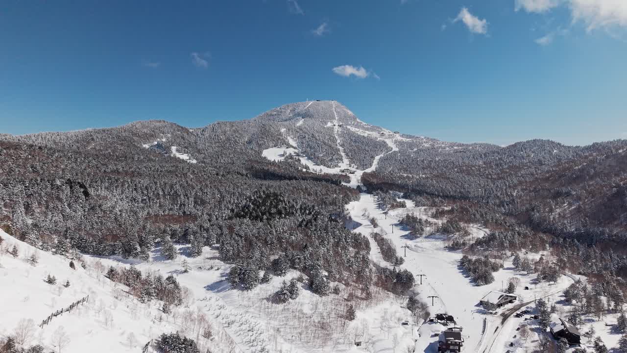 Aerial drone footage flying towards Mount Yokote ski resort in winter snow