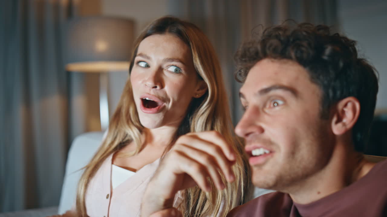 Excited pair watching horror movie resting home closeup. Family feeling scared