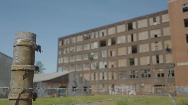 Ripresa al rallentatore di una recinzione di filo spinato con un edificio abbandonato situato a Cleveland, Ohio.