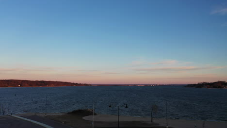 an aerial shot of a light and flag pole with a bay in the background