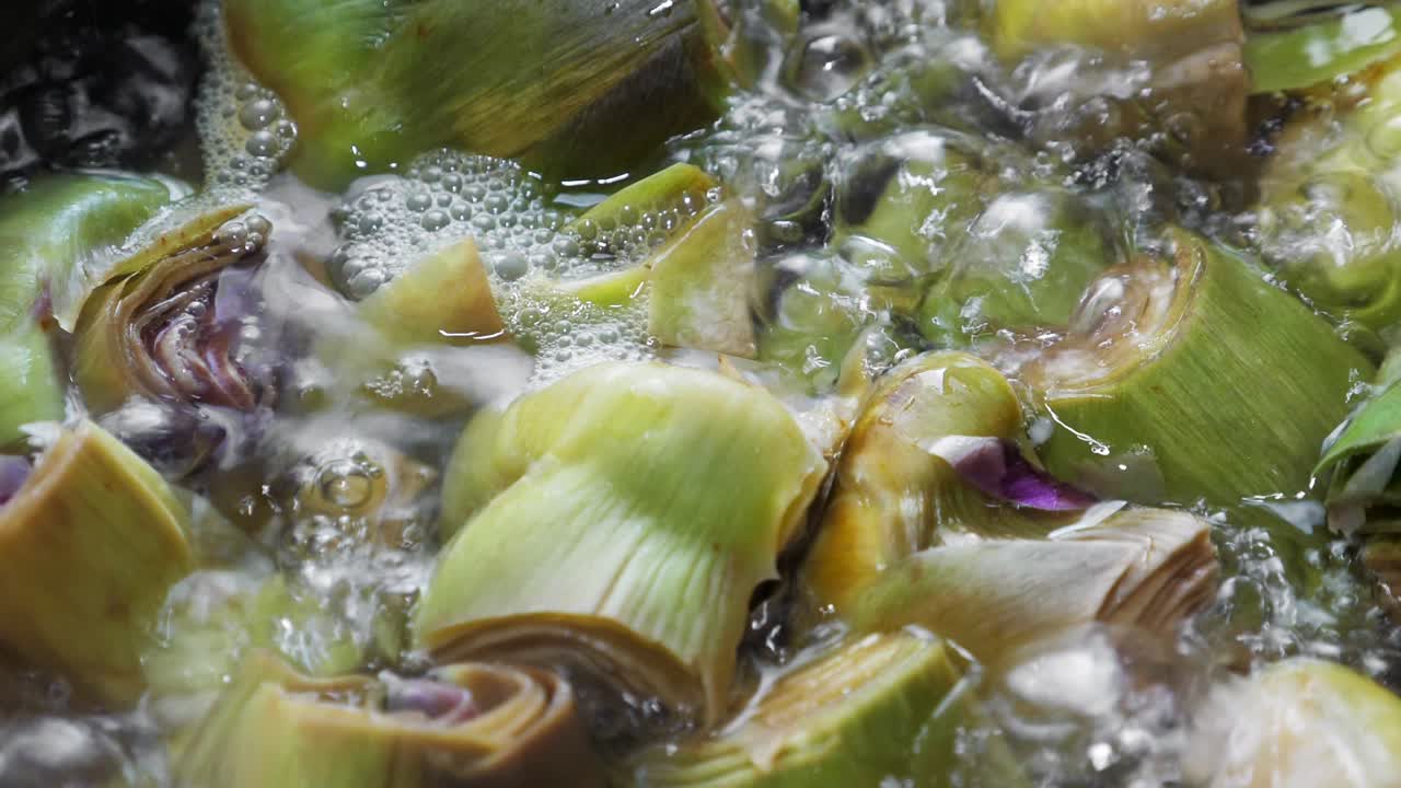 Boiling and cooking artichokes in saucepan, closeup