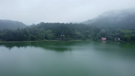 Old-chapel-on-shore-of-low-cloud-overcast-lake-on-lush-green-Azores